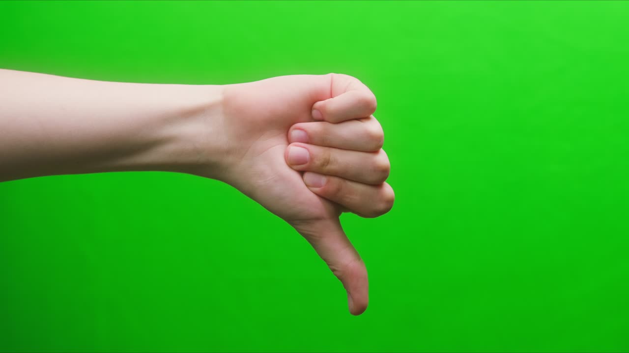 Close-up of a hand gesture on a green background, dislike gesture, shooting a gesturing in studio