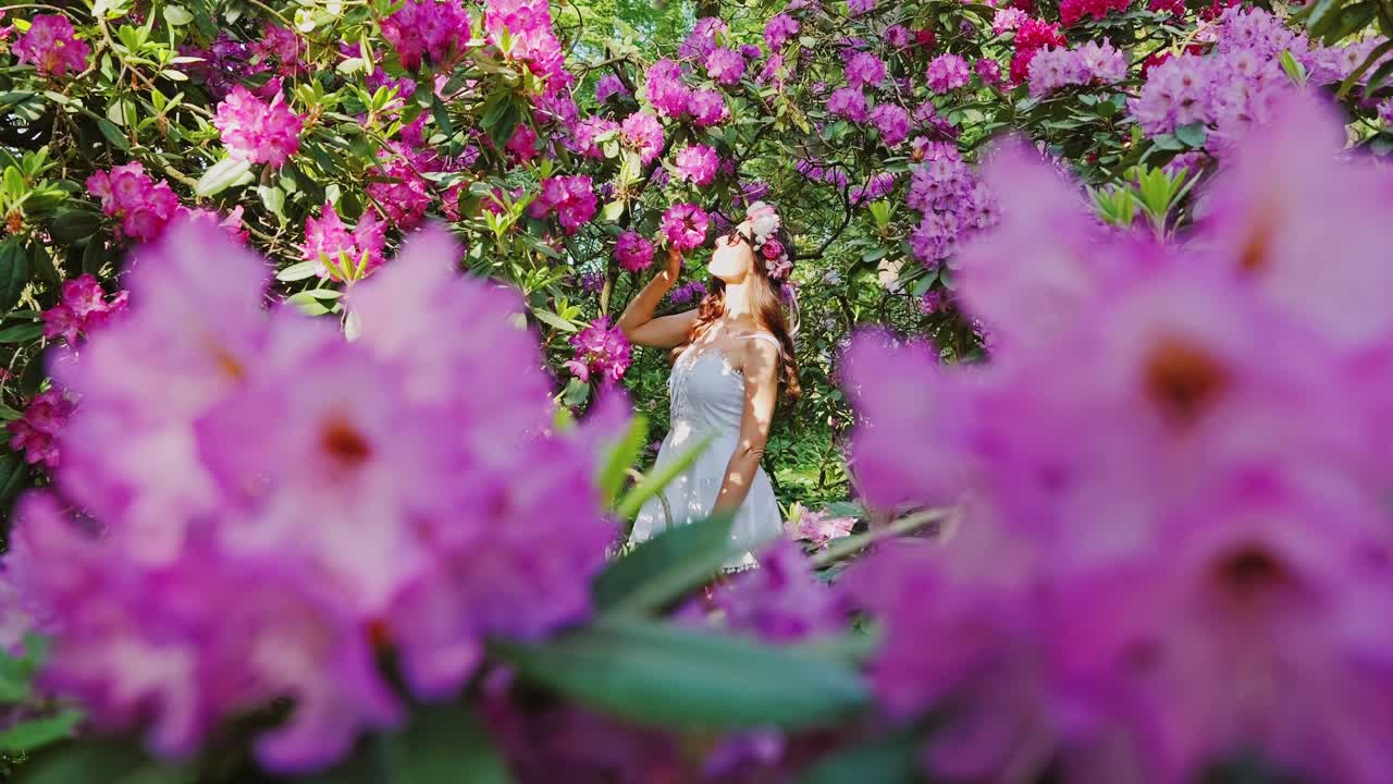 Spring garden in bloom as woman in floral crown smells flower branch gently