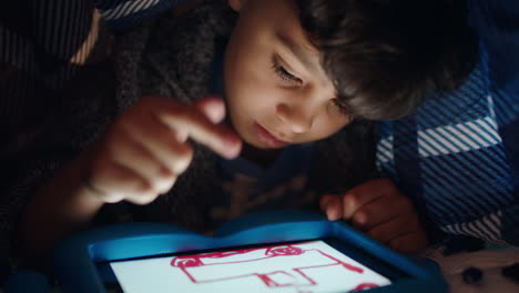Un-Niño-Lindo-Usando-Una-Tableta-Digital-Debajo-De-Una-Manta-Disfrutando-Dibujando-En-La-Tecnología-De-Pantalla-Táctil-Jugando-Juegos-Divirtiéndose-A-La-Hora-De-Dormir