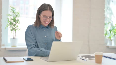successful young woman celebrating on laptop at work