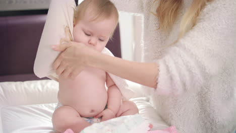 mom undressing baby. infant going for a walk. baby unclothing on bed