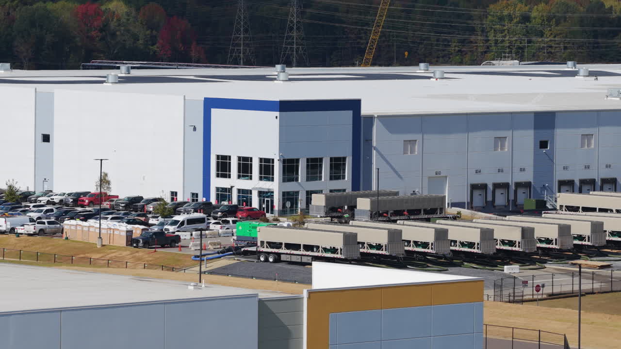 Tight aerial shot sliding right past mobile generator units staged outside a large data facility