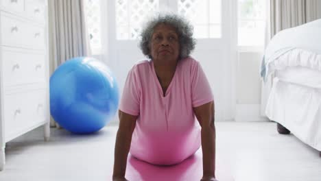 Senior-african-american-woman-performing-exercise-in-bedroom-at-home