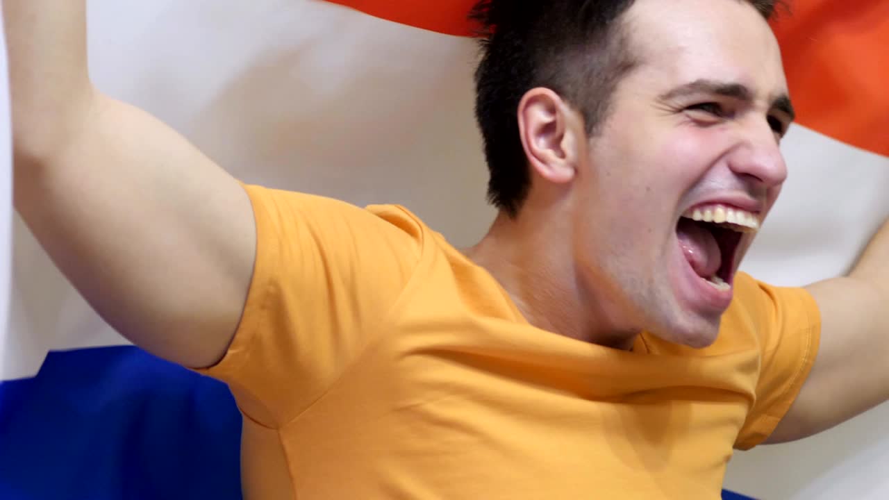 países bajos joven celebrando mientras sostiene la bandera de los países bajos en cámara lenta