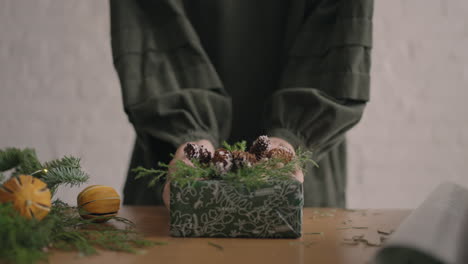 a christmas present moves a woman's hands into the camera. green packaged gift woman moves into camera after packing and decorating