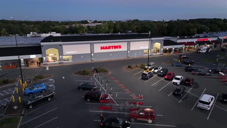 parking cars in front of american shopping mall at dusk. pharmacy and martins storefront in virginia. aerial approaching shot.