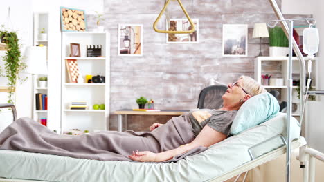 retired disabled lady lying in hospital bed in cozy and bright room in retirement home