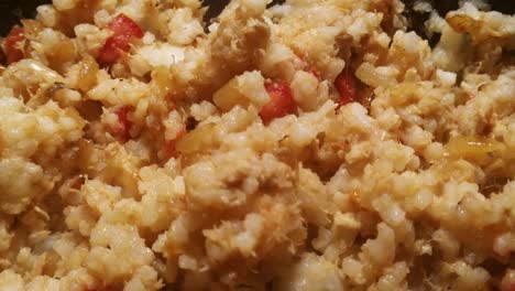 Close-up-hovering-over-freshly-cooked-stir-fried-rice-with-tuna,-peppers-and-onions-that-has-a-golden-colour