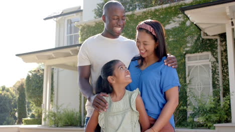 smiling family of three standing together outside their home, enjoying time together