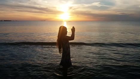 la joven medita en la playa al atardecer