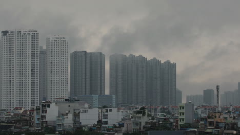 atmospheric shot of urban area with large high-rise apartment buildings with fasst moving morning fog, clouds or pollution