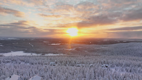 aerial view a arctic sunset behind mountain huts and and frozen forest of lapland