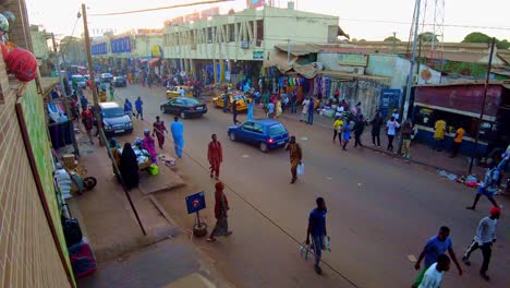 bustling serekunda market street with cars, people, and vendors during sunset