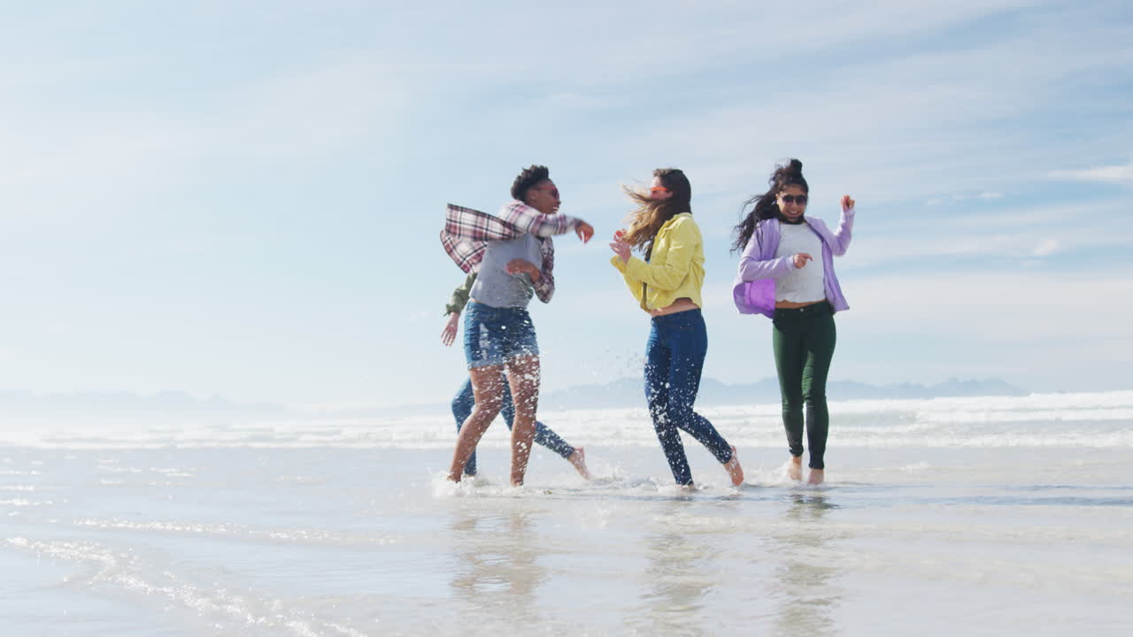 다양한 여성 친구들의 행복한 그룹이 해변에서 재미있고, 춤추고, 미소 짓고 있습니다.