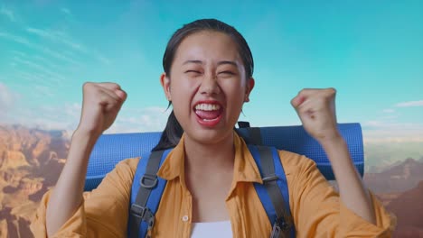 close up of asian female hiker with mountaineering backpack screaming goal celebrating the success while traveling at the top of mountain