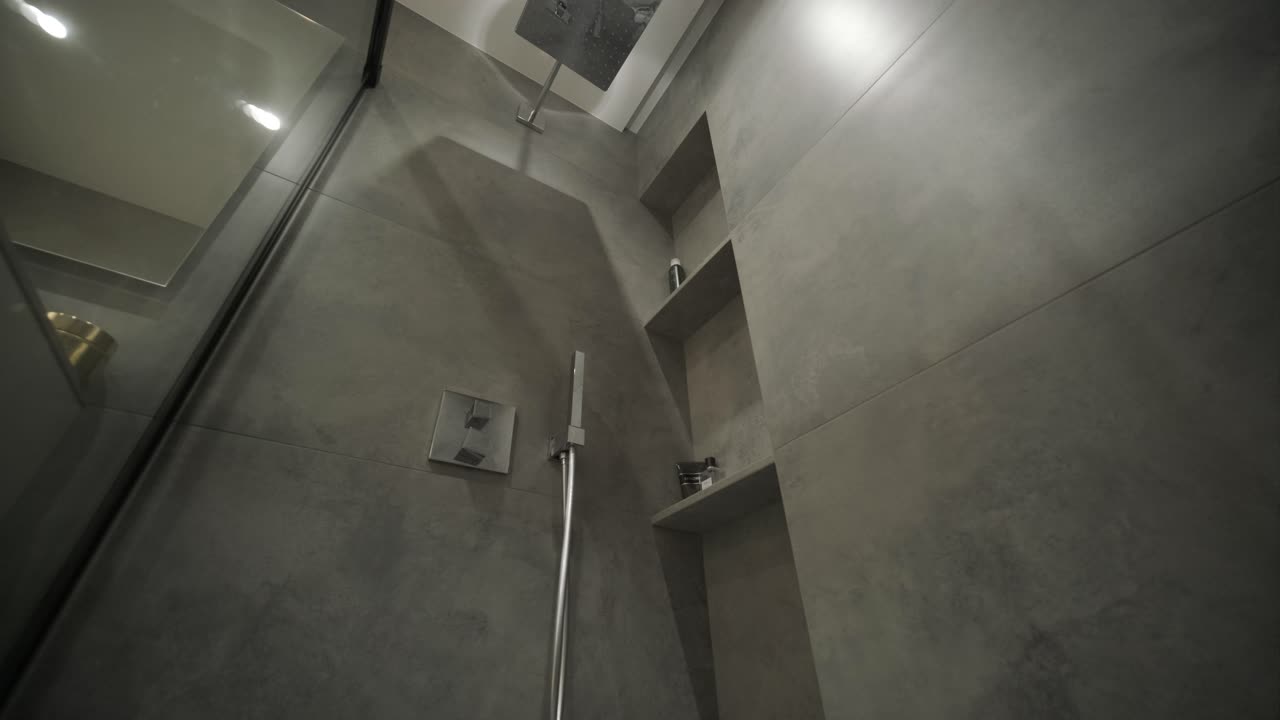 Modern minimalistic bathroom interior design with grey stone tiles, black furniture, eucalyptus in glass vase, round mirror. Aesthetic simple interior design concept.