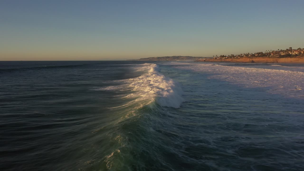 매혹적인 드론 샷은 드론이 해안으로 따라가는 일몰 동안 부서지는 파도를 포착하고 충격에서 안개가 뿜어져 나와 바다의 힘과 아름다움을 보여줍니다.