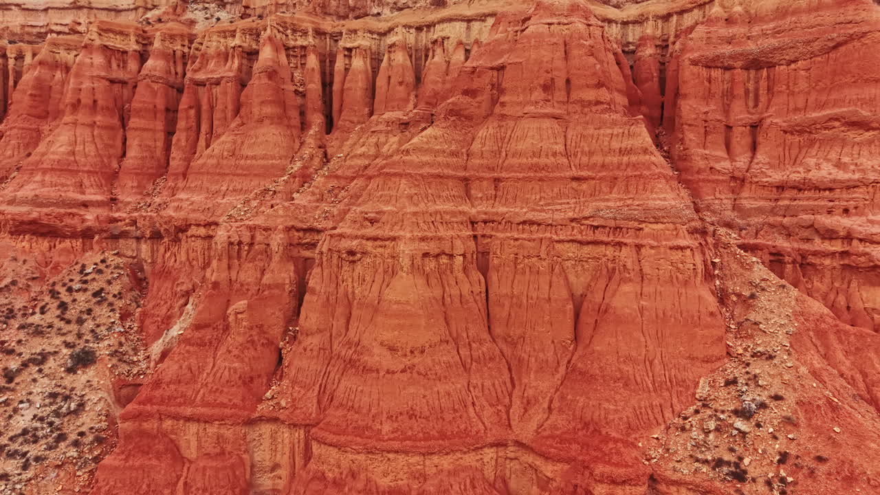 Un paesaggio canyon mostra formazioni rocciose e stratificazioni dai colori vivaci con texture definite alla luce del giorno.