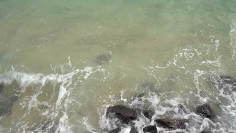 turquoise ocean waves breaking on sandy and rocks coastline