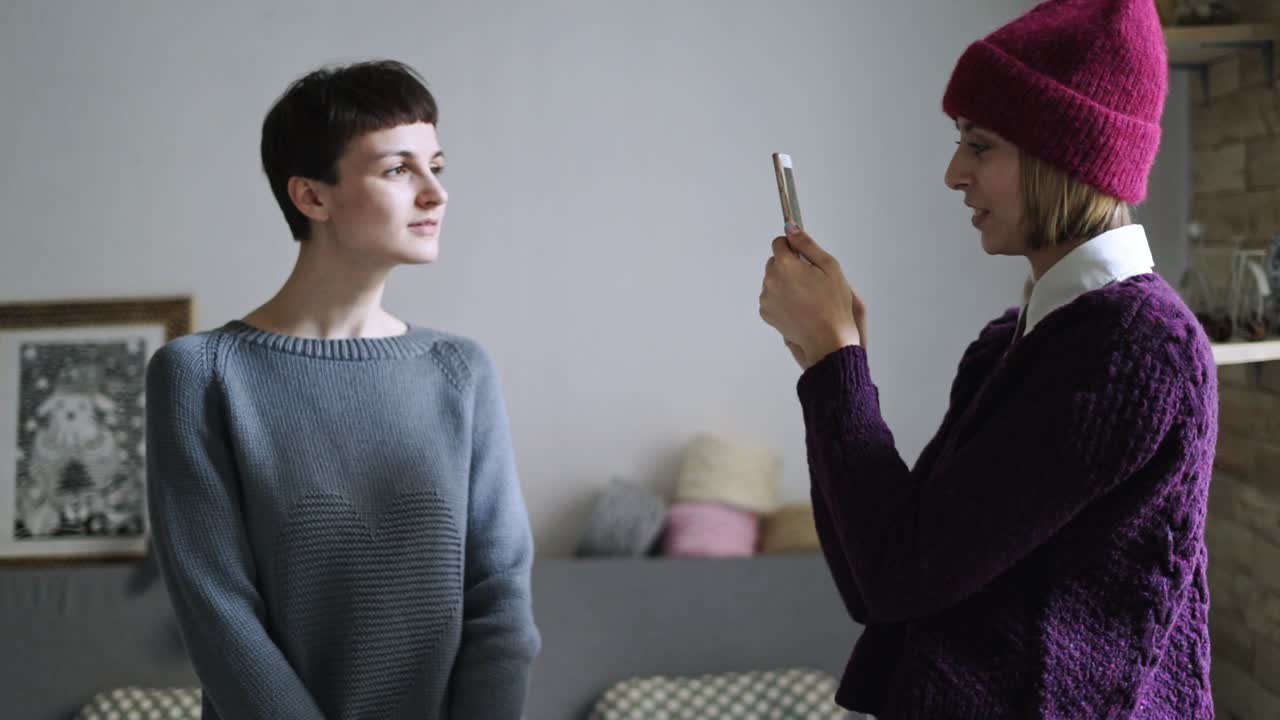mujer fotografiando a un amigo en el teléfono móvil. mujer hipster haciendo una foto