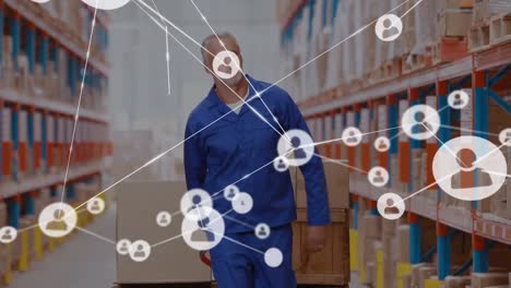 animation of network of people icons over caucasian man working in warehouse moving boxes