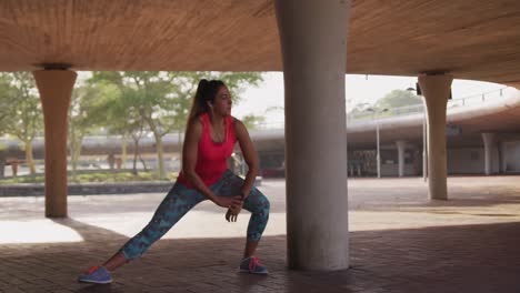 mujer caucásica estirándose debajo de un puente