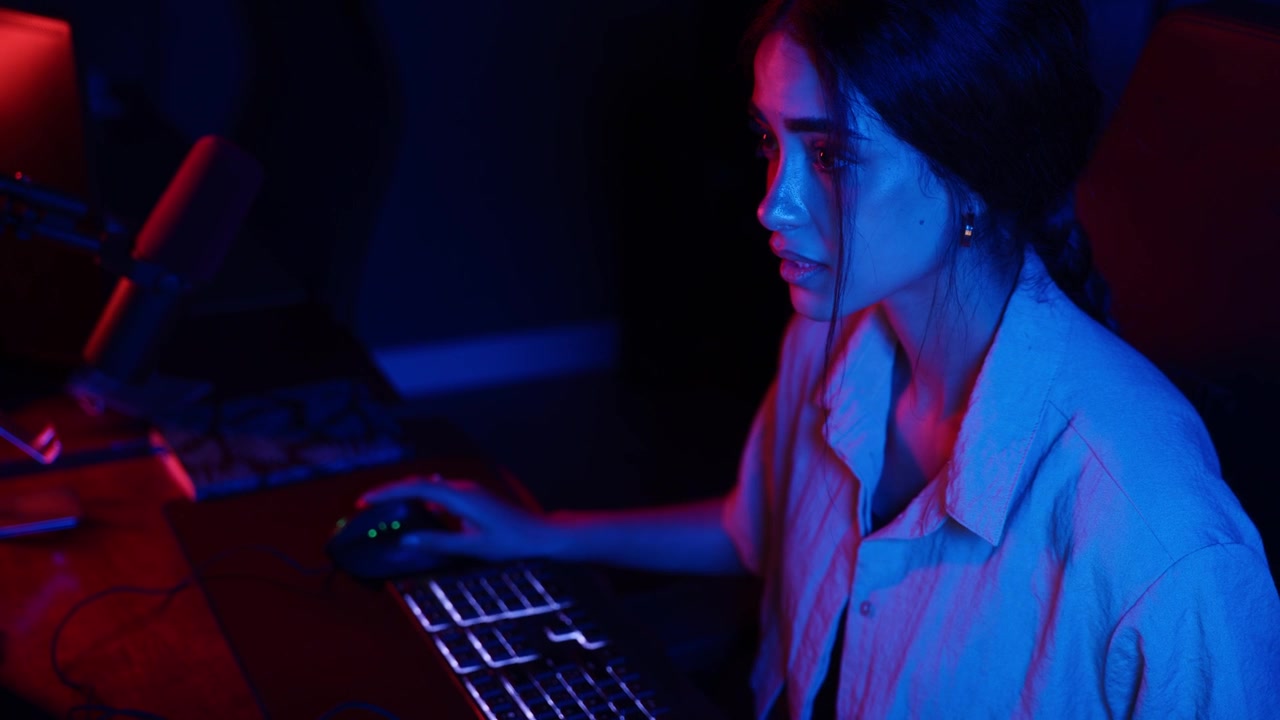 Young Woman Working on Computer in Dark Room with Neon Lighting