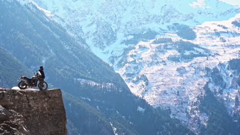 un hombre parado con su bicicleta y fumando al borde del acantilado en el punto de suicidio, kalpa, himachal pradesh