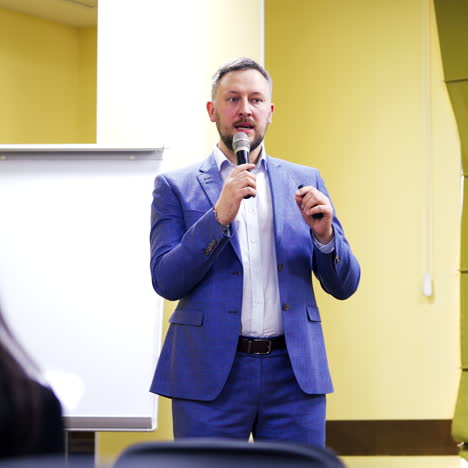 Male speaker conducts speech and smiling to the audience at the conference meeting. Seminar with a professional lecturer in auditorium. Conference concept.