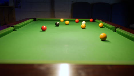 Slider-shot-of-pool-player-potting-a-yellow-ball-on-a-pol-table-in-a-pub-bar