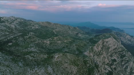 wide forward aerial of the biokovo mountains in cloudy croatia at dusk