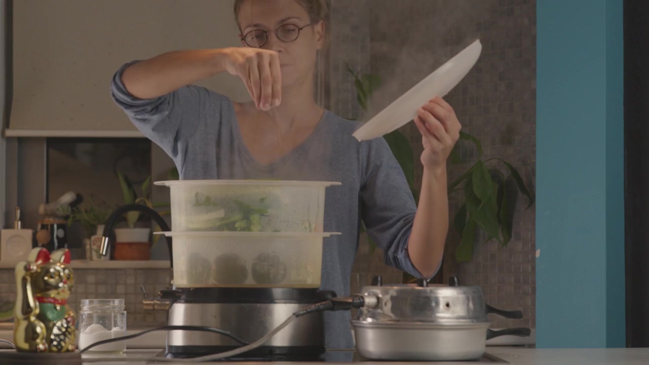 A woman cooking in her kitchen using a steam cooker.