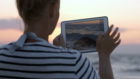 mujer tomando fotos de las olas del mar con una almohadilla