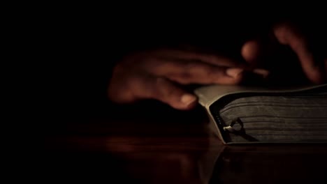 Praying-to-God-with-hand-on-bible-black-background-with-people-stock-footage-5