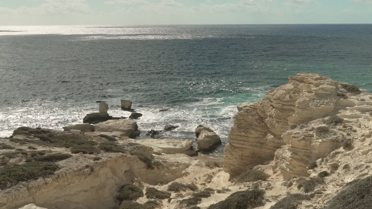 Discover a beautiful coastal landscape featuring unique rock formations and gentle waves under a clear sky, perfect for a relaxing experience by the sea
