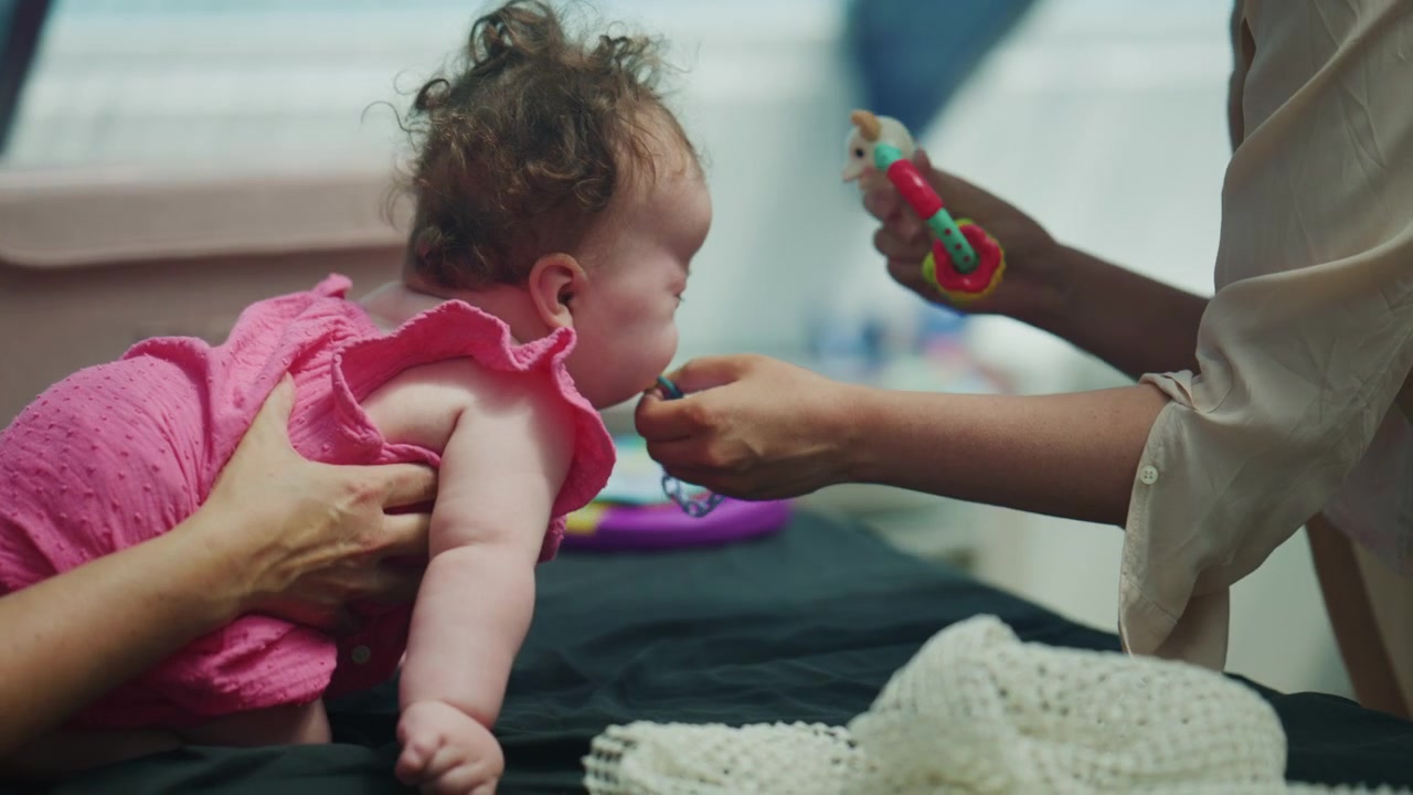 Rear view of an infant practicing tummy time and supported mobility exercises with caregivers, promoting neck strength, posture control, and early childhood physical development