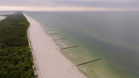 Aerial view around wavebreakers on a long beach, dramatic sunset in Hel, Poland