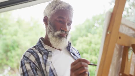 video of african american senior man painting picture outside