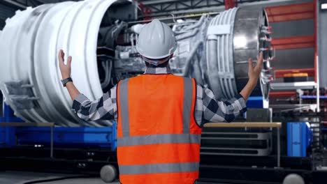 back view of a male engineer with safety helmet spreading arms while standing with airplane engine maintenance conducted, analytics checking the turbine