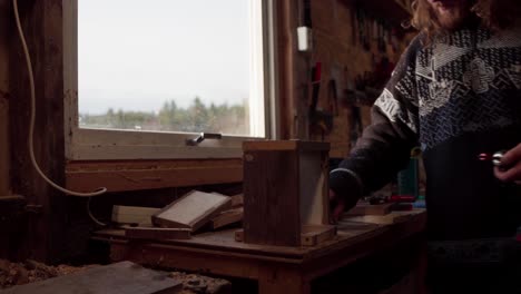 hombre ocupado en su taller haciendo caja de madera y sujetar con un tornillo