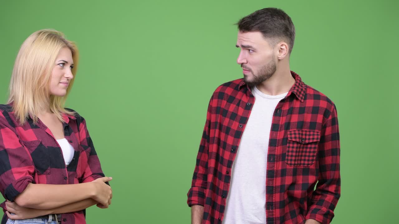 Young woman whispering to young man and looking displeased