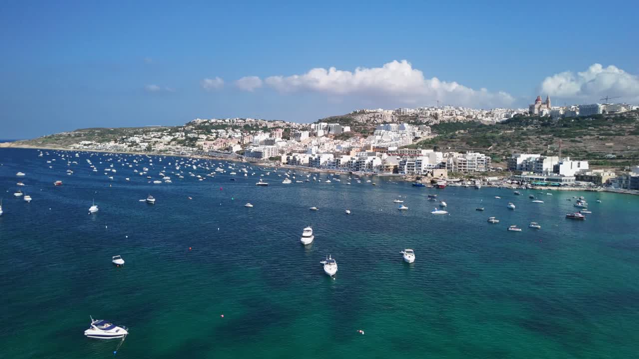 Aerial view of a busy harbor with boats, clear skies, and coastal city