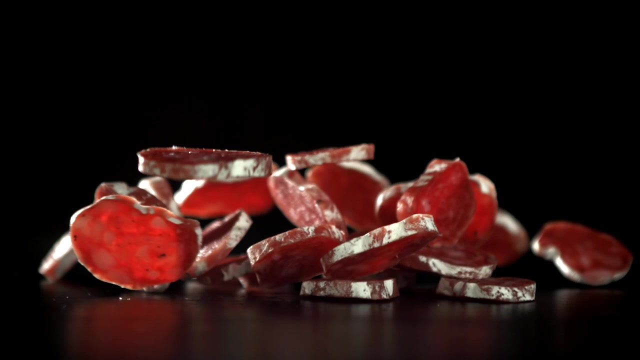 Salami Slices Falling in Slow Motion on Black Background