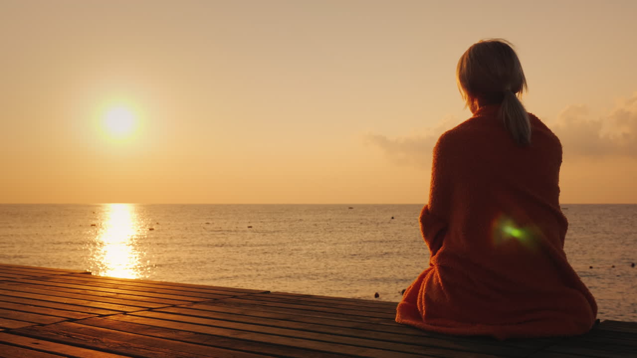 바다의 아침 - 수건으로 싸인 여성이 일출 4k 비디오를 만납니다.