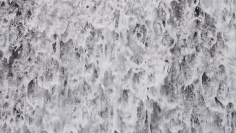 close-up of water splashing down a waterfall, creating white foam and dynamic natural flow