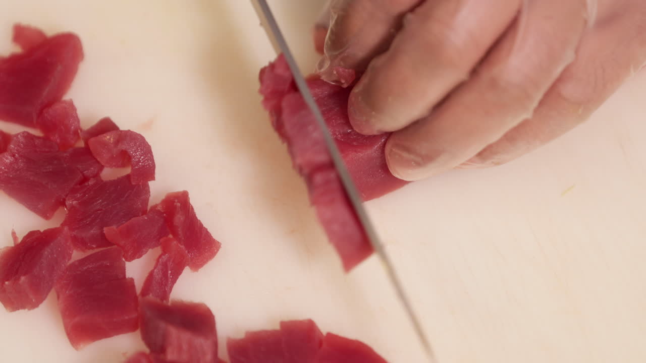 흰 도마에 칼을 사용하여 참치 고기를 자르는 일본 요리사