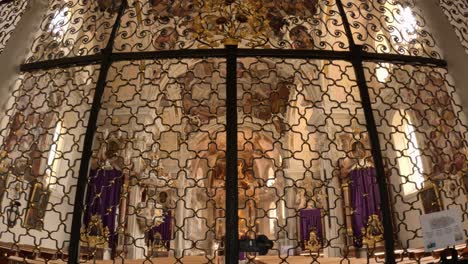 interior detail of the basilica in innsbruck showing an elaborate wrought iron screen with golden accents and baroque ornamentation, separating the main nave from the sanctuary area