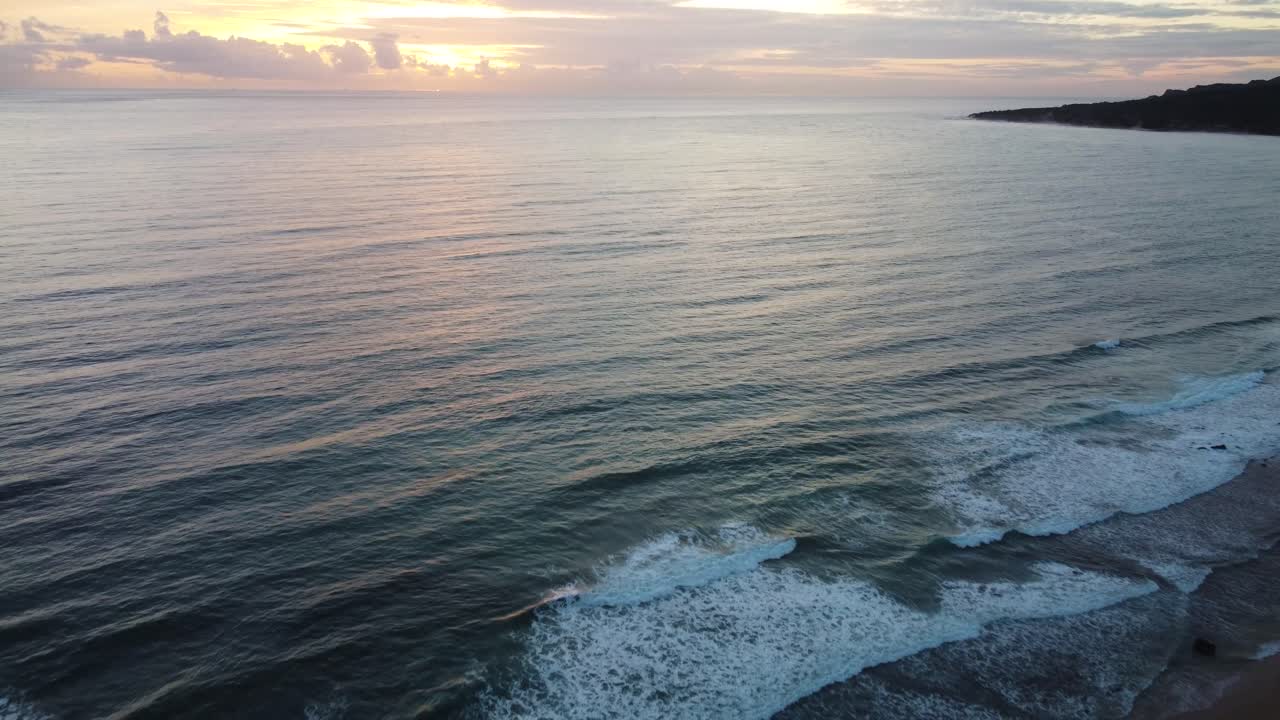 Onde che si infrangono sulla costa spagnola con il cielo al tramonto, vista aerea.