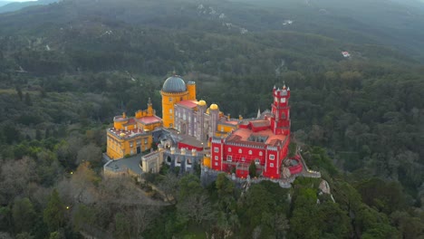 Luftrückzug-Farbenfroher-Pena-Palast-Auf-Einem-Steilen-Hügel,-Umgeben-Von-Wald,-Sintra