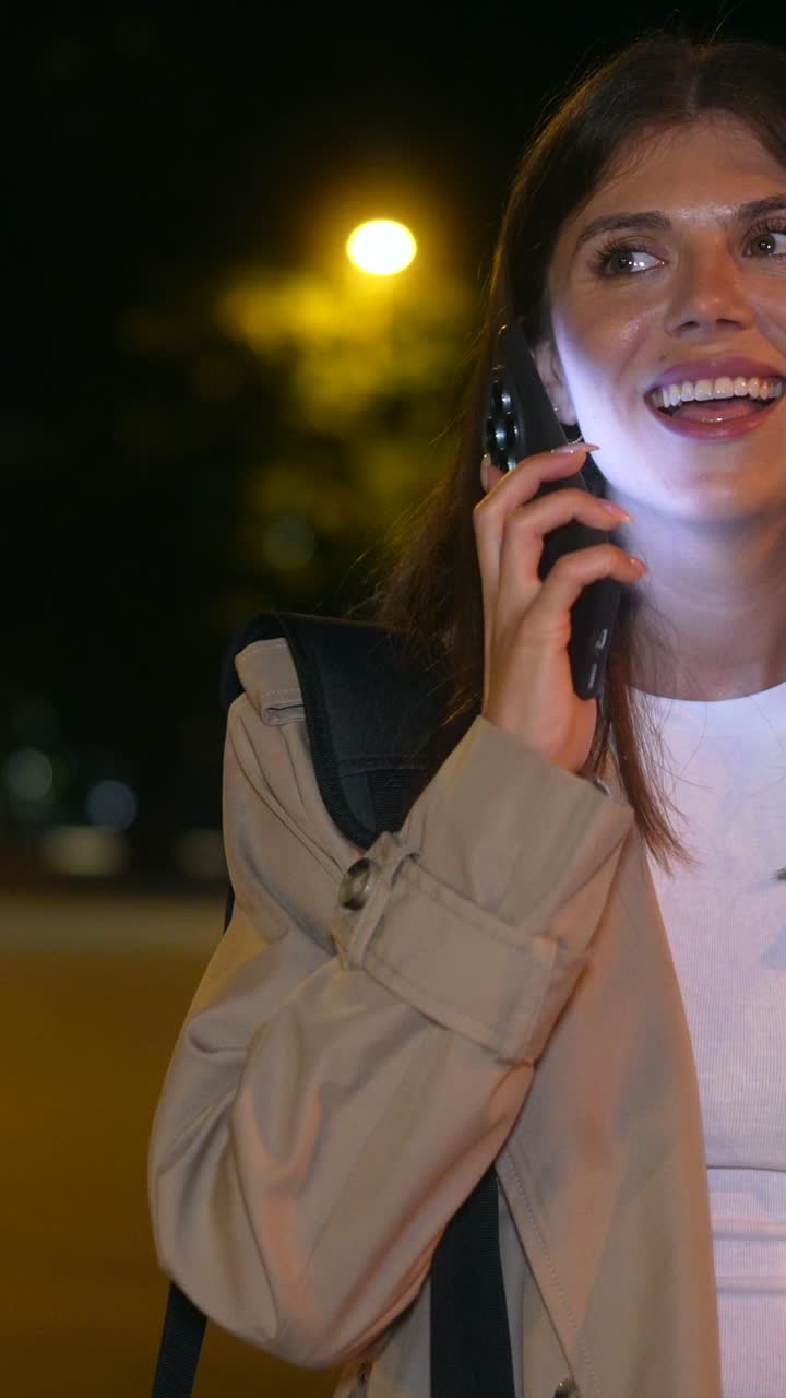Donna sorridente che usa il telefono di notte